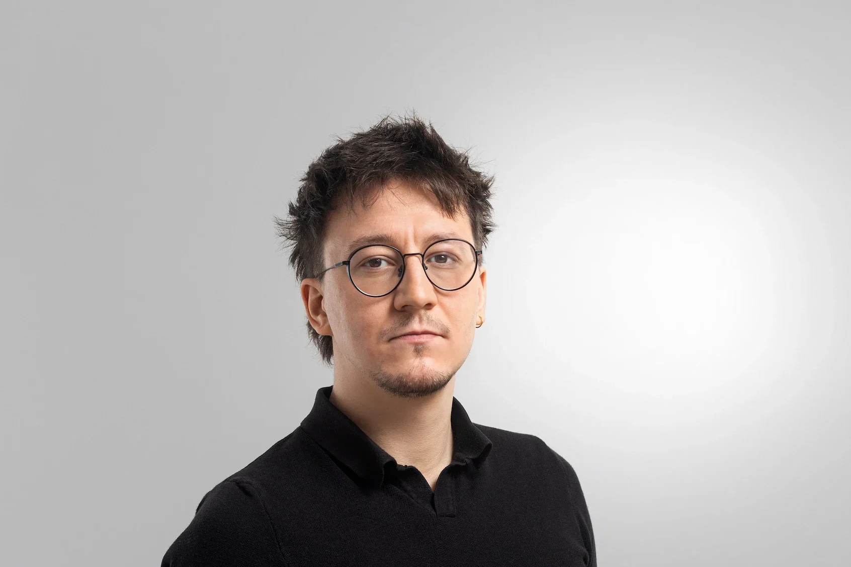 Muž v černém tričku, neutrální pozadí.